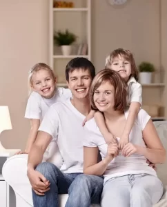 "Image: A joyful family of four smiling inside a brightly lit, clean home. The environment appears mold-free, emphasizing comfort and healthiness."